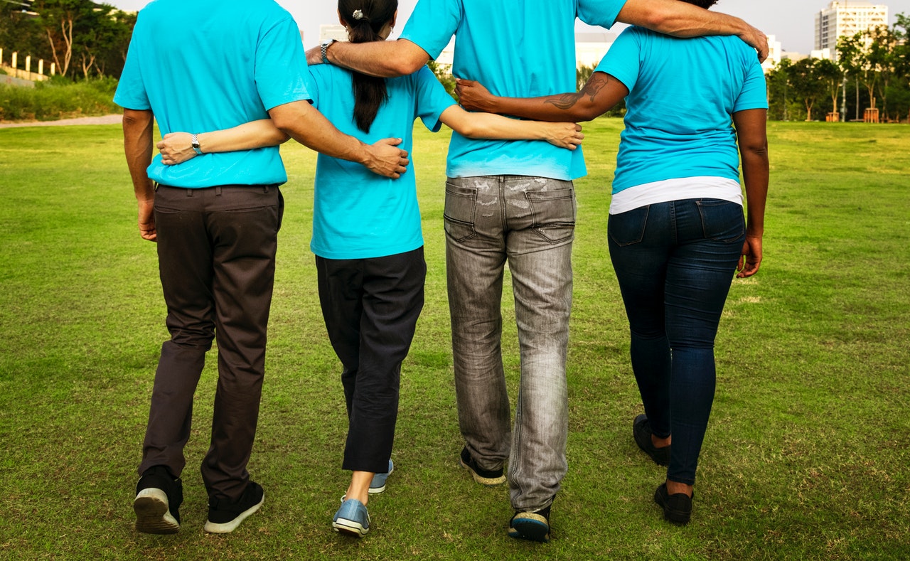 Four People Walking While Holding Each Others Arms